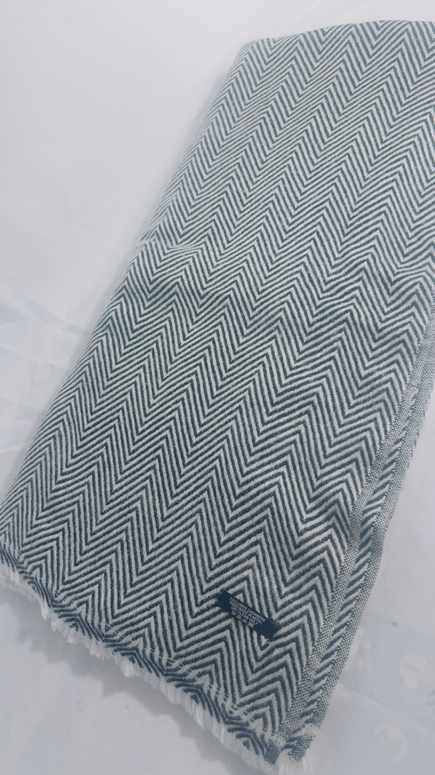 Grey and white herringbone cashmere blanket laid flat showing full pattern and fringe