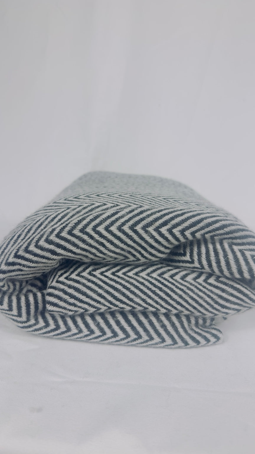 Folded grey and white herringbone cashmere blanket showing texture and pattern