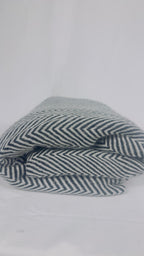 Folded grey and white herringbone cashmere blanket showing texture and pattern
