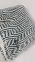 Grey and white herringbone cashmere blanket detail with care label and fringe