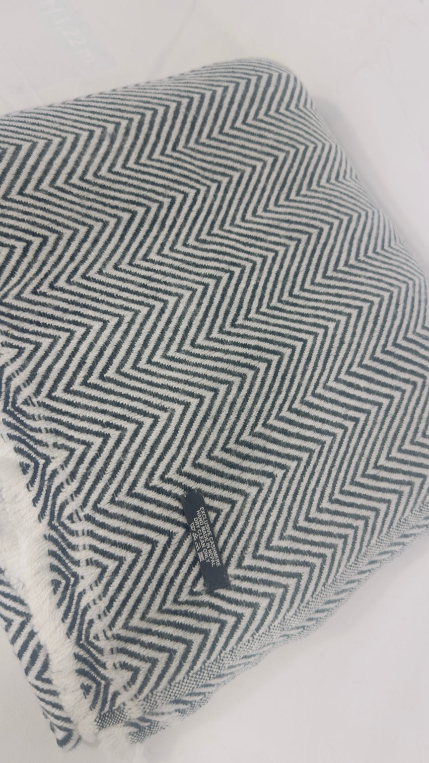 Grey and white herringbone cashmere blanket detail with care label and fringe