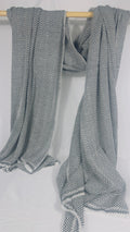 Grey and white herringbone cashmere blanket draped over a wooden rail