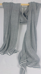 Grey and white herringbone cashmere blanket draped over a wooden rail