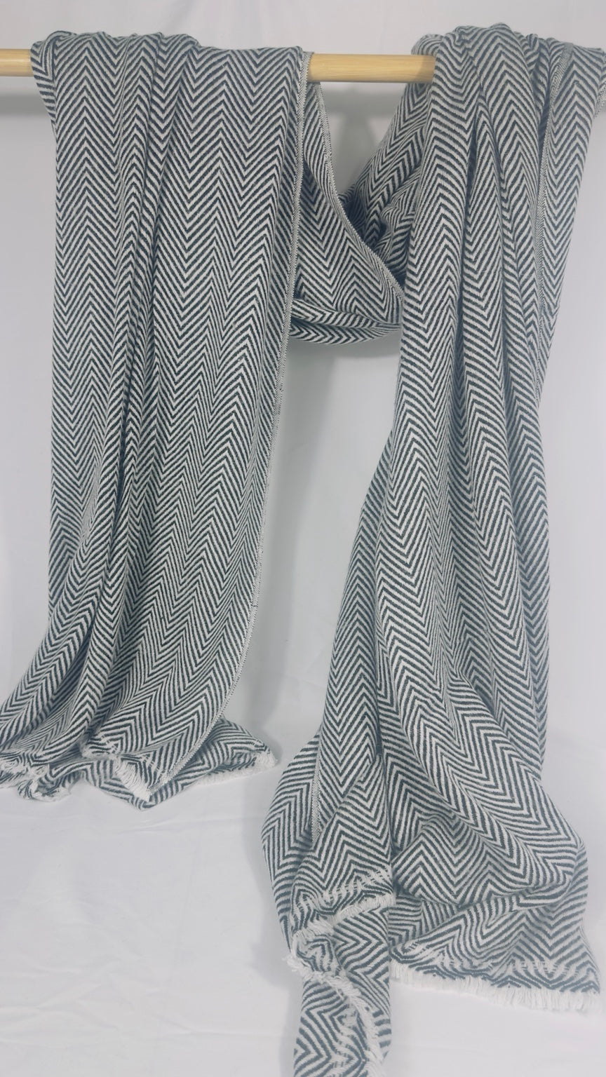 Grey and white herringbone cashmere blanket draped over a wooden rail
