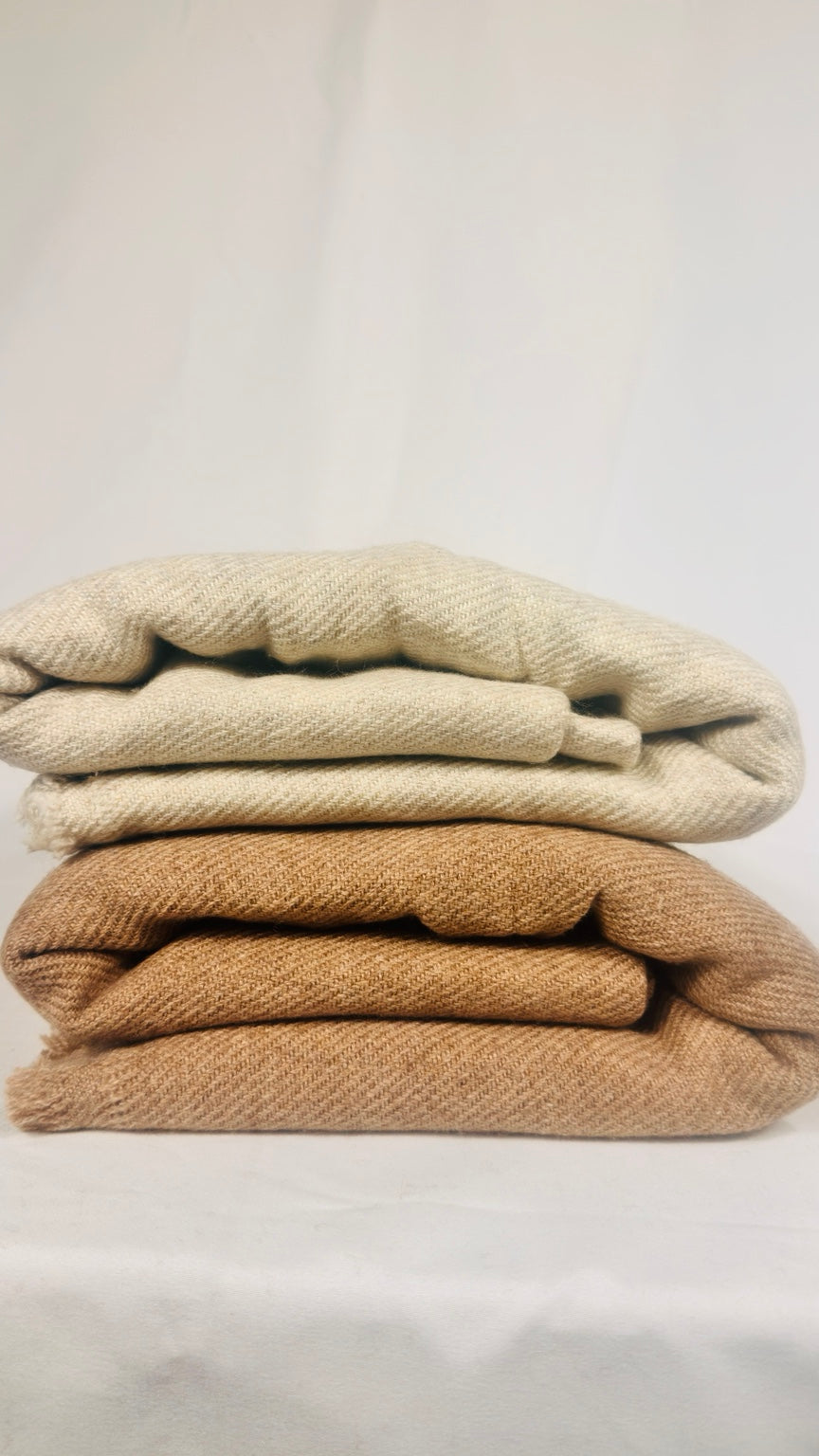 White plain cashmere blanket draped over a wooden rail