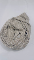 Beige herringbone cashmere scarf styled in a soft rolled arrangement