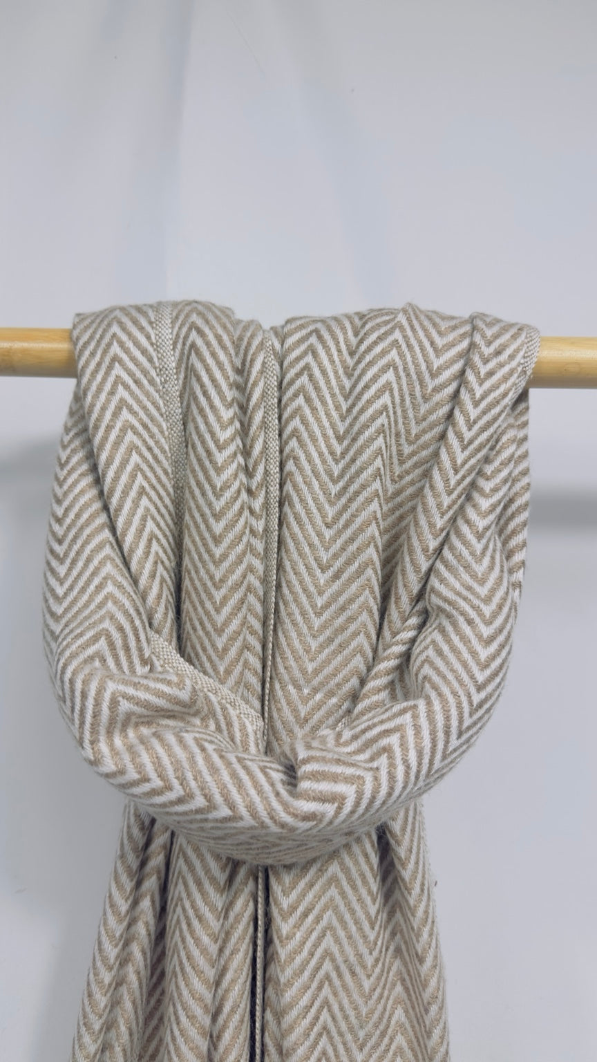 Beige herringbone cashmere scarf knotted on a wooden rail