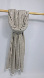Full length beige herringbone cashmere scarf hanging on a wooden rail